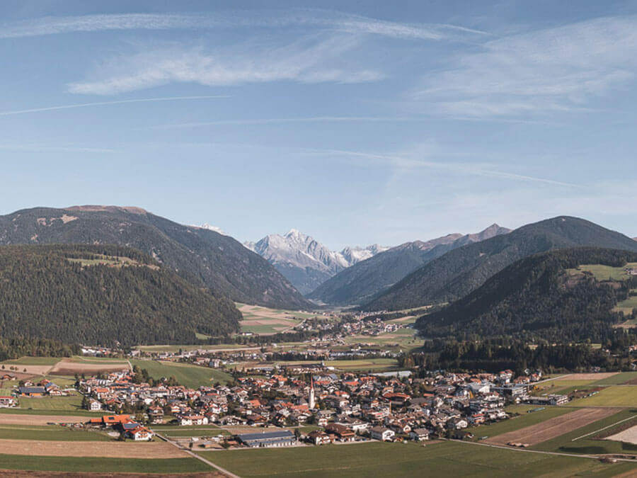 A town in a valley with mountains in the background. - Pension Pfarrwirt